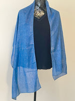 Blue printed scarf woven with sparkly lurex threads draped over a black top.