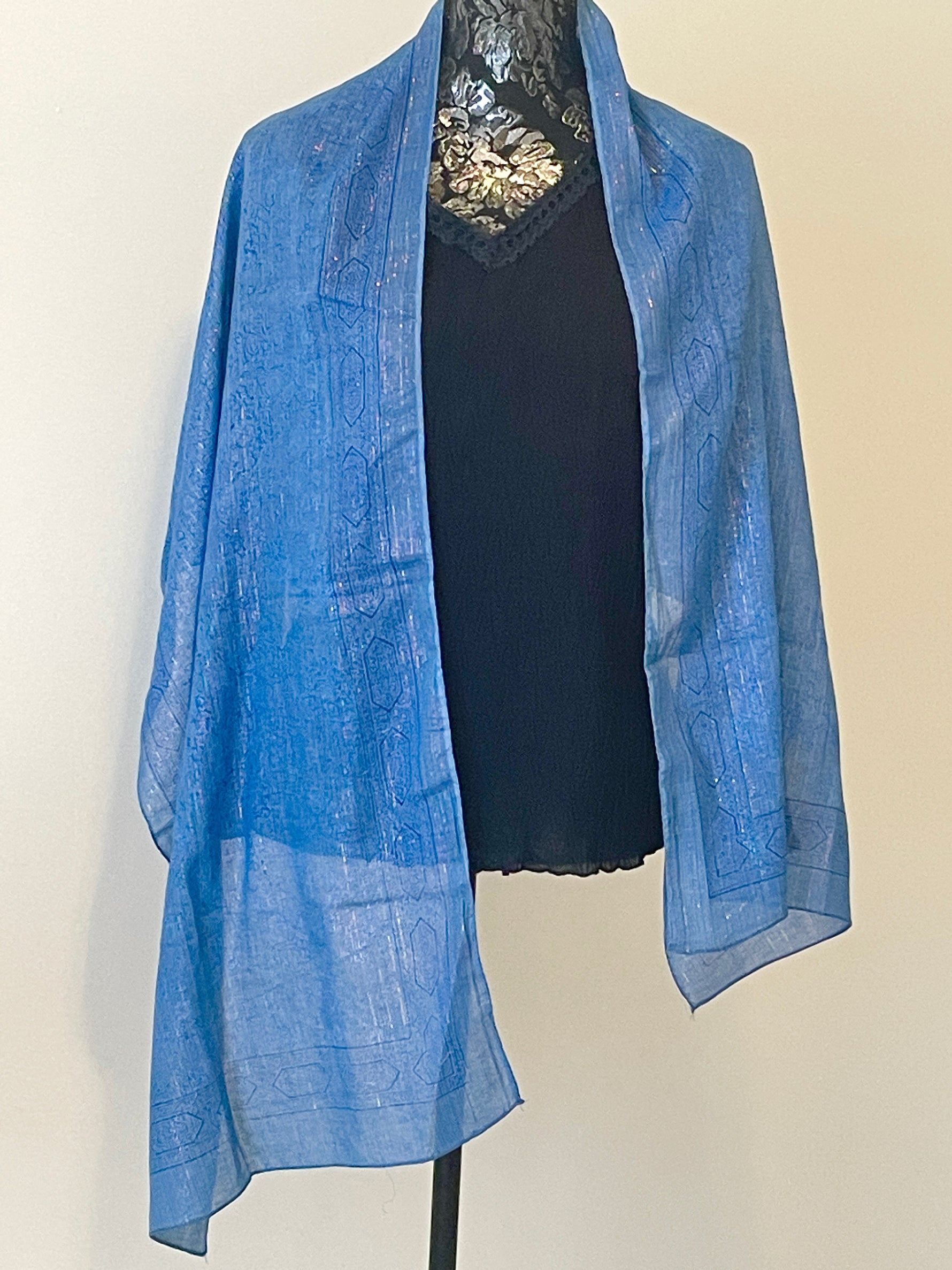 Blue printed scarf woven with sparkly lurex threads draped over a black top.