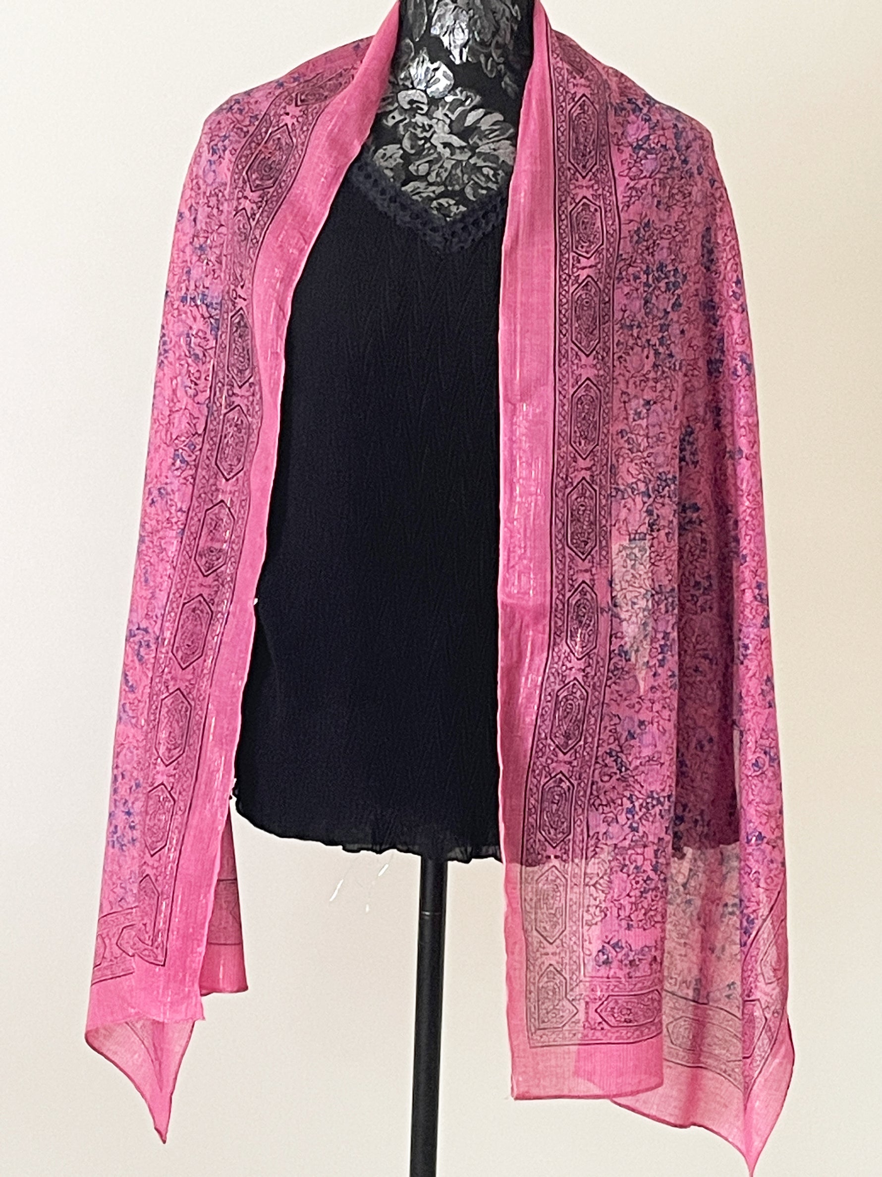 Dark pink printed scarf woven with sparkly lurex threads draped over a black top.