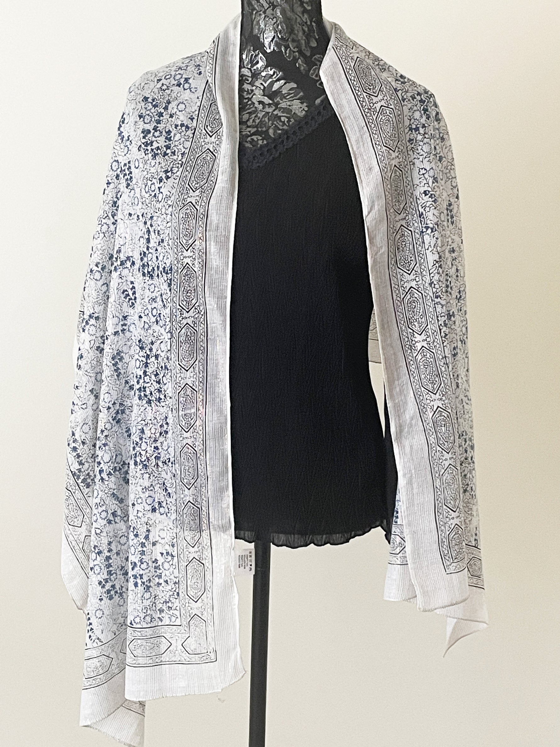 Ivory printed scarf woven with sparkly lurex threads draped over a black top.